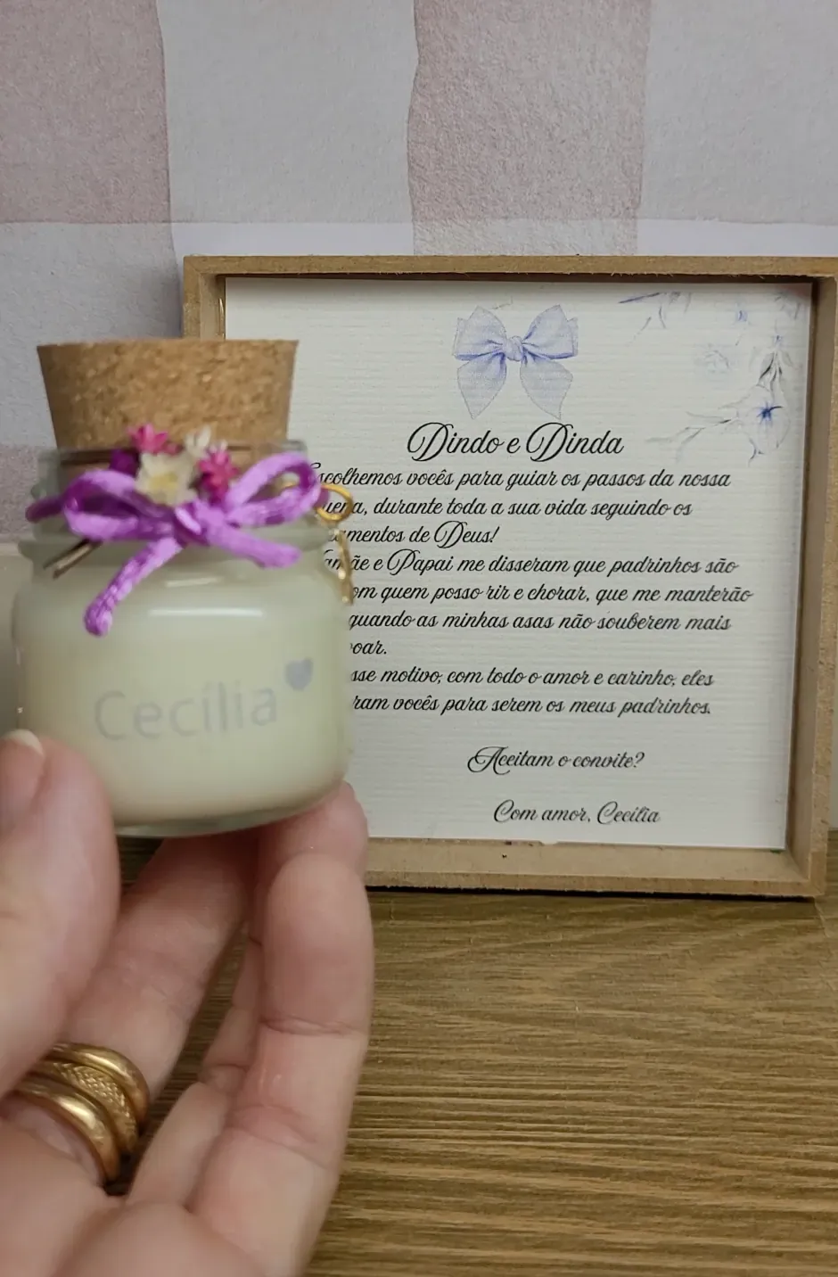 Vela com laço lilás e quadro com o convite para dindo e dinda